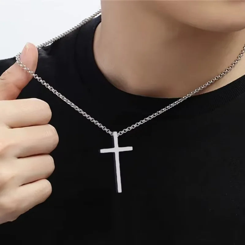 Person wearing a silver cross necklace on a plain background
