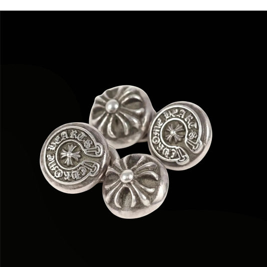 Four silver buttons with decorative designs on a black background