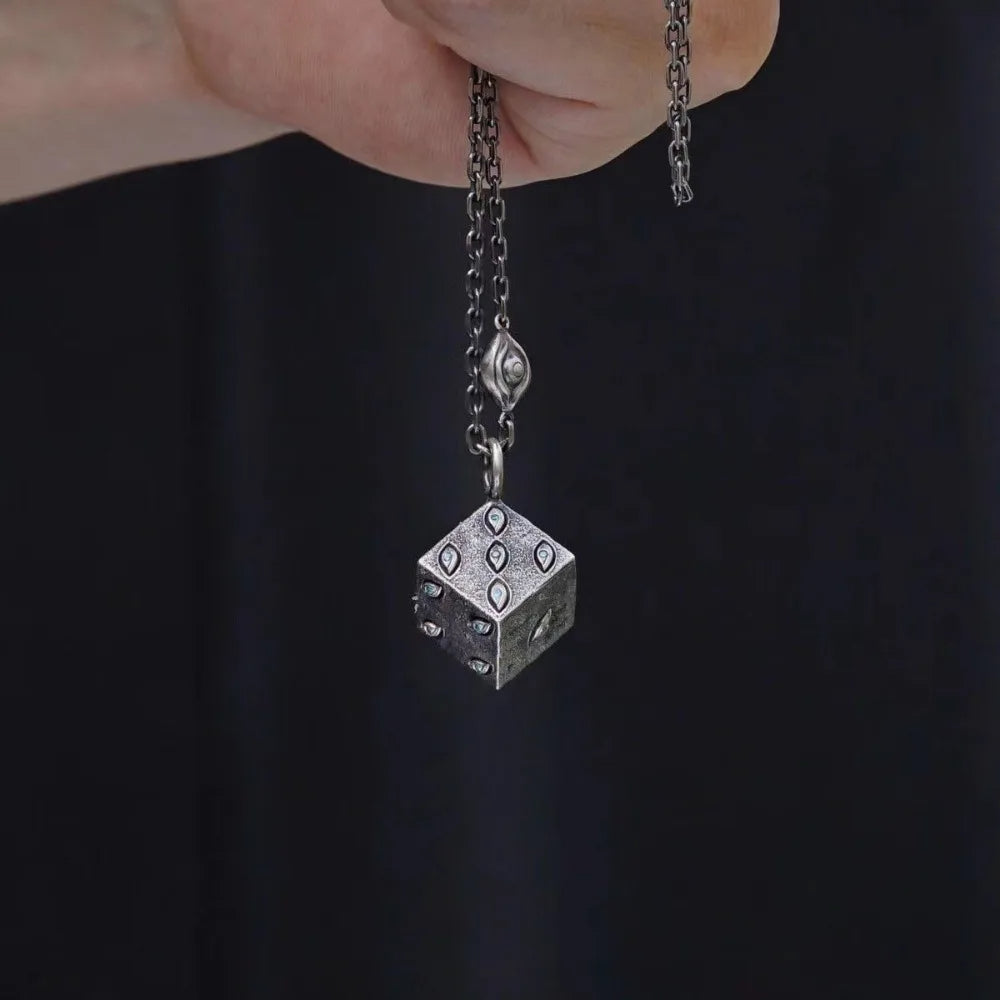 Silver necklace with a dice pendant against a dark background