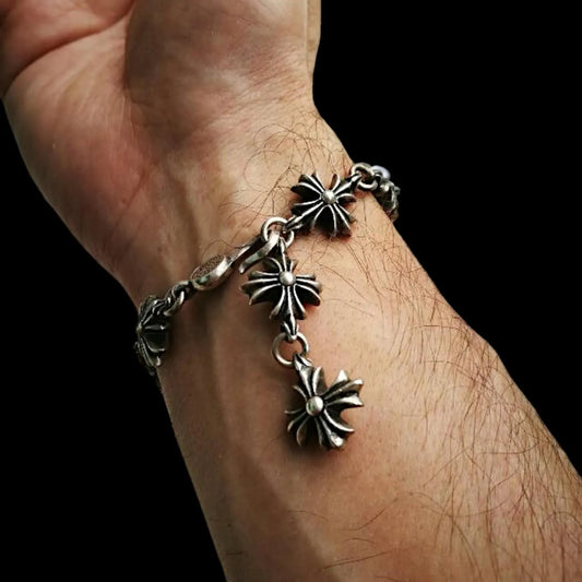 Silver bracelet with star-shaped charms on a wrist against a dark background.
