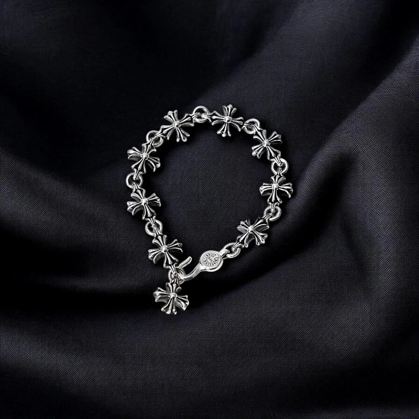 Silver bracelet with floral designs on black satin fabric