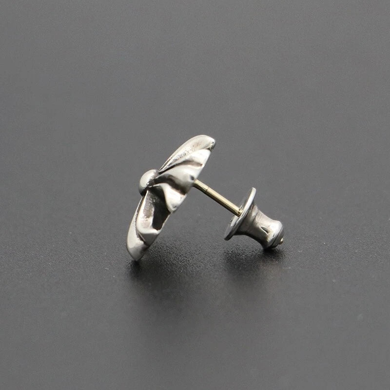 Silver wing-shaped earring on a dark gray background