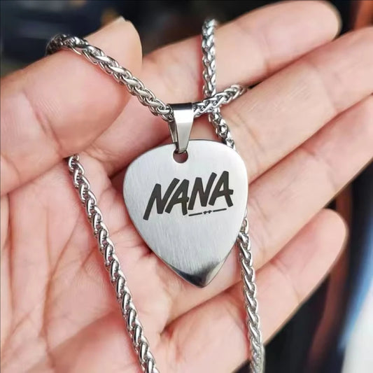 Heart-shaped silver pendant with 'NANA' engraved, held in a hand.