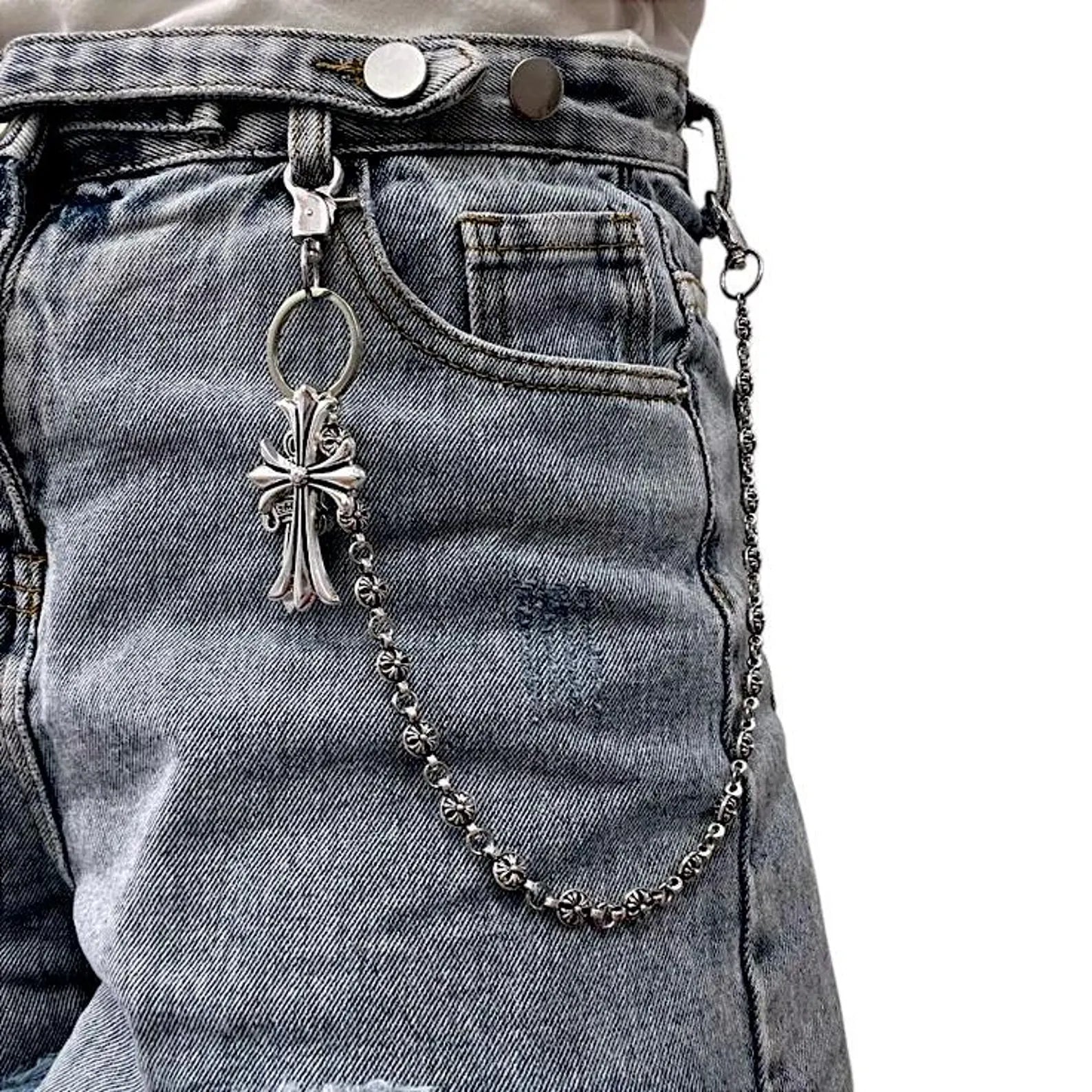 Metallic keychain with cross pendant attached to a denim jacket.
