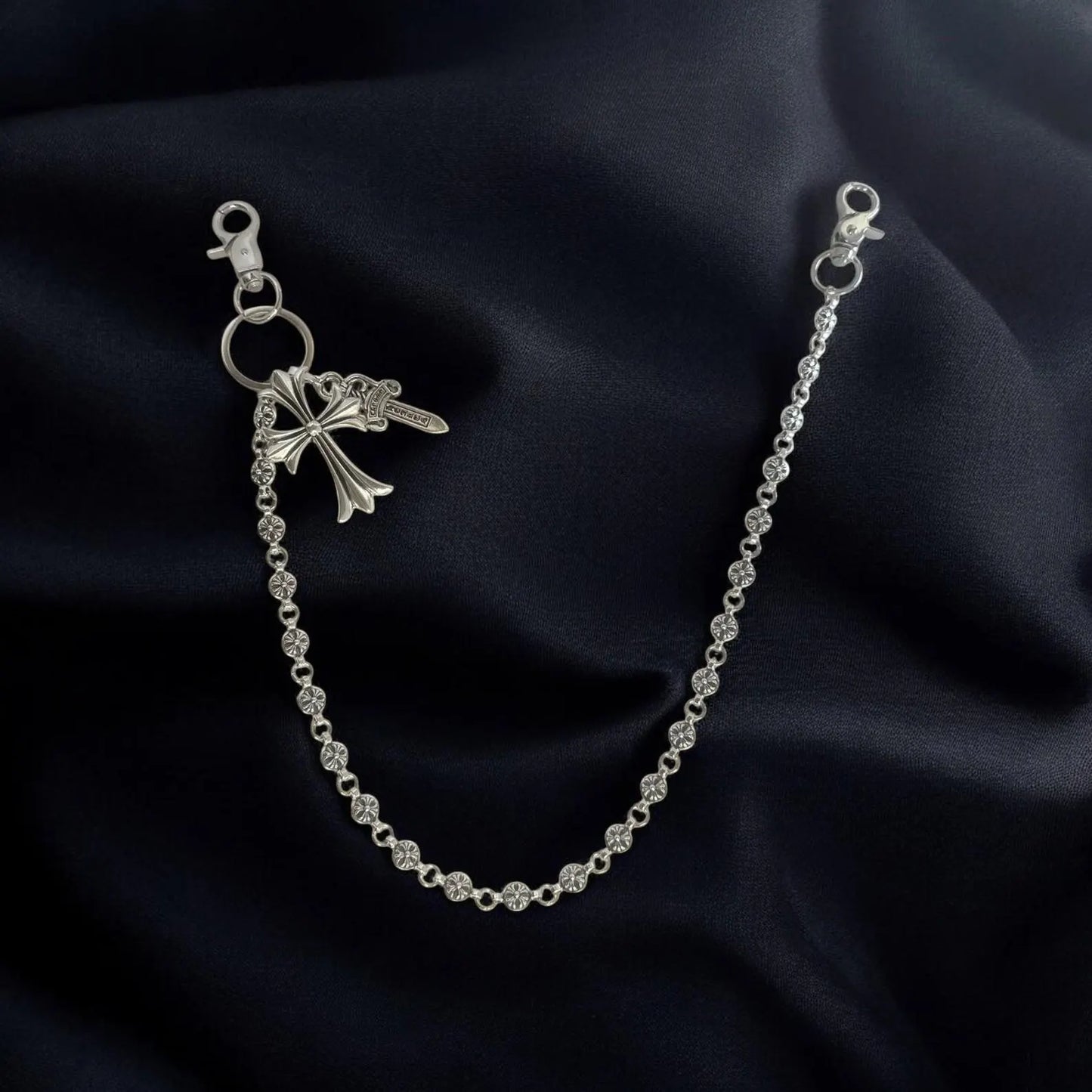 Silver chain bracelet with a bow-shaped clasp on a dark fabric background