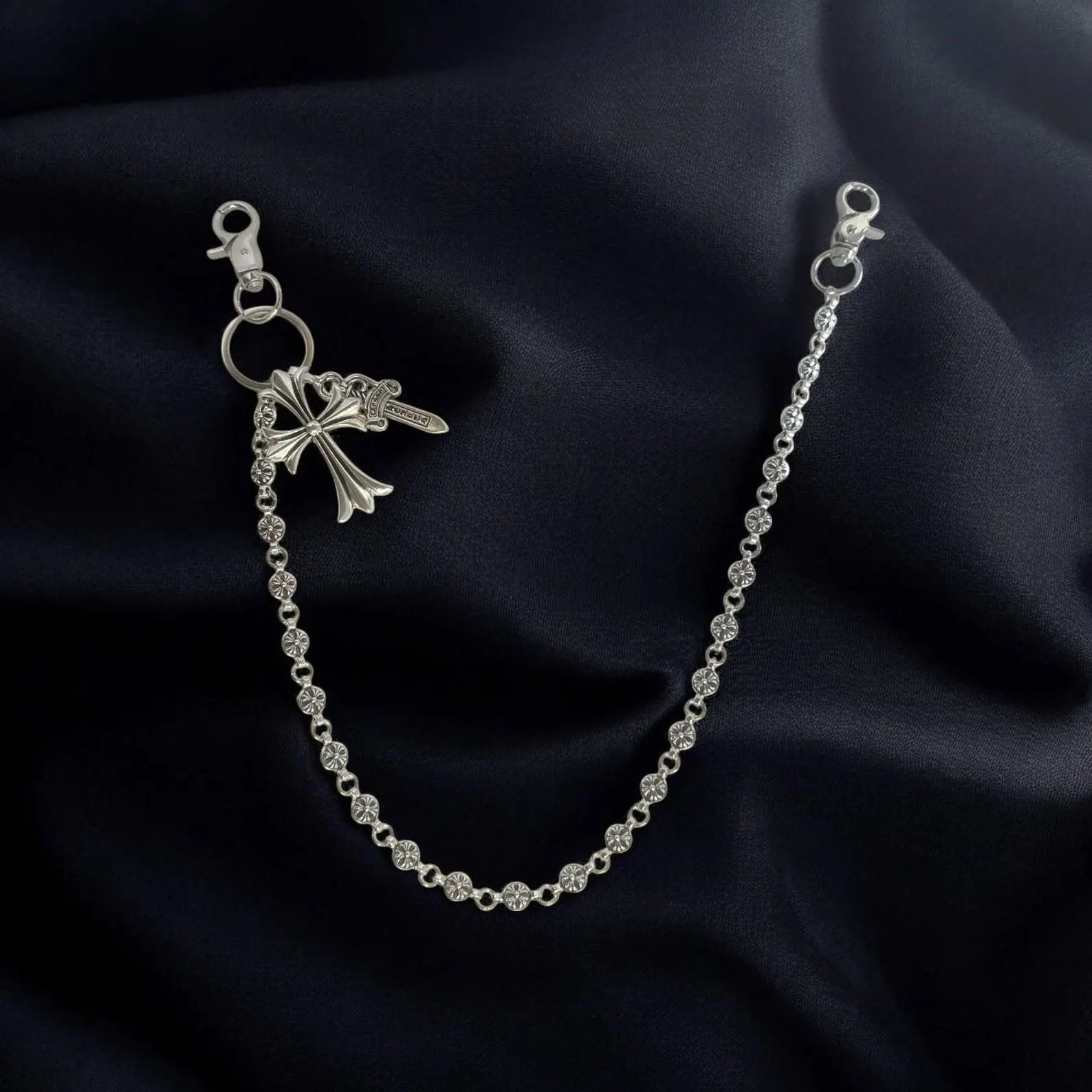Silver chain bracelet with a bow-shaped clasp on a dark fabric background