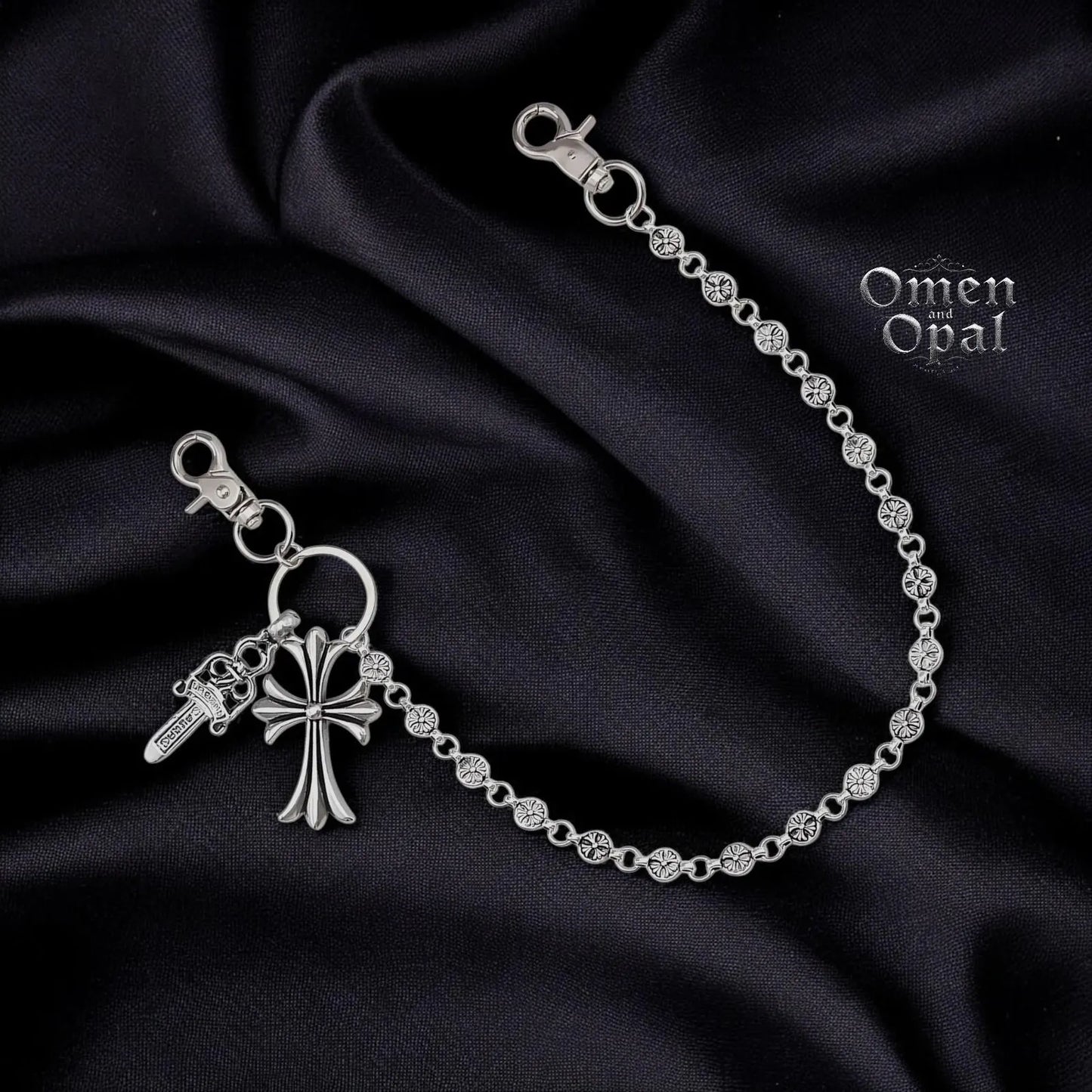 Silver bracelet with key and cross charm on a dark fabric background
