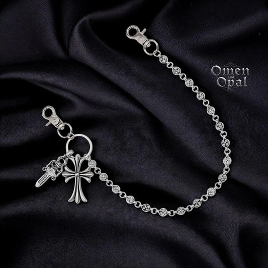 Silver bracelet with key and cross charm on a dark fabric background